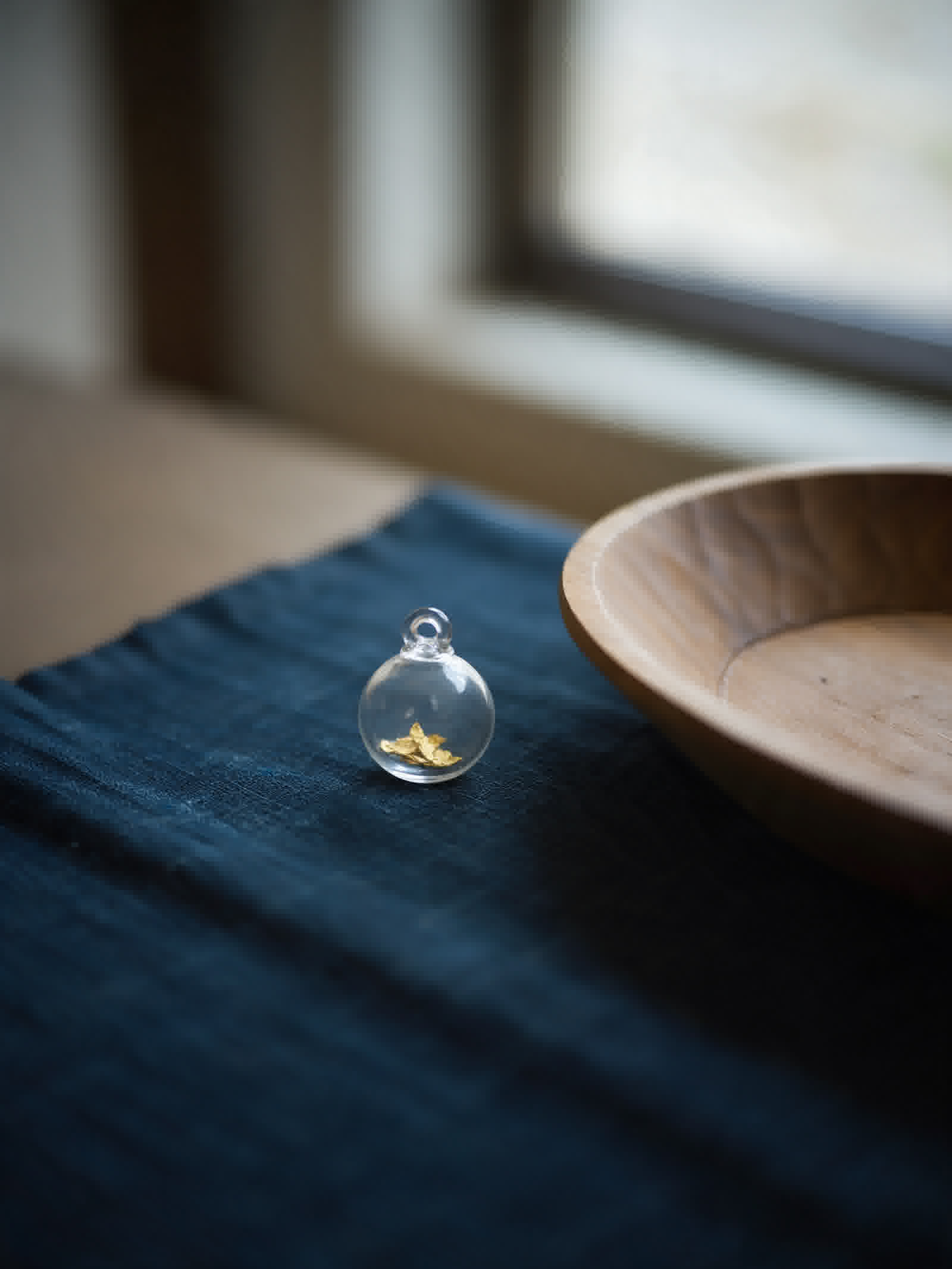 Small glass pendant holding flakes of natural gold
