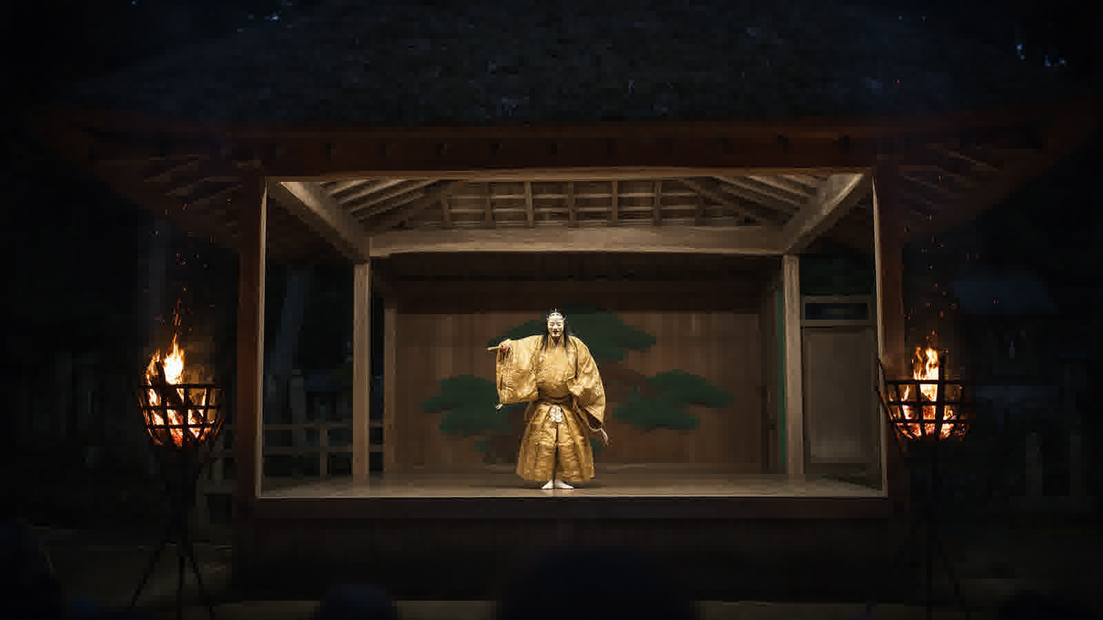 Open-air Noh stage lit by torches in a shrine grove